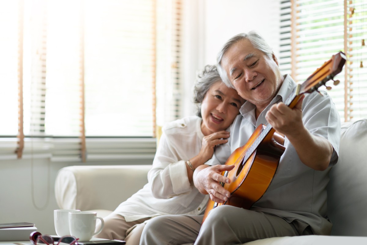 older Asian couple enjoys time together playing guitar 291520979