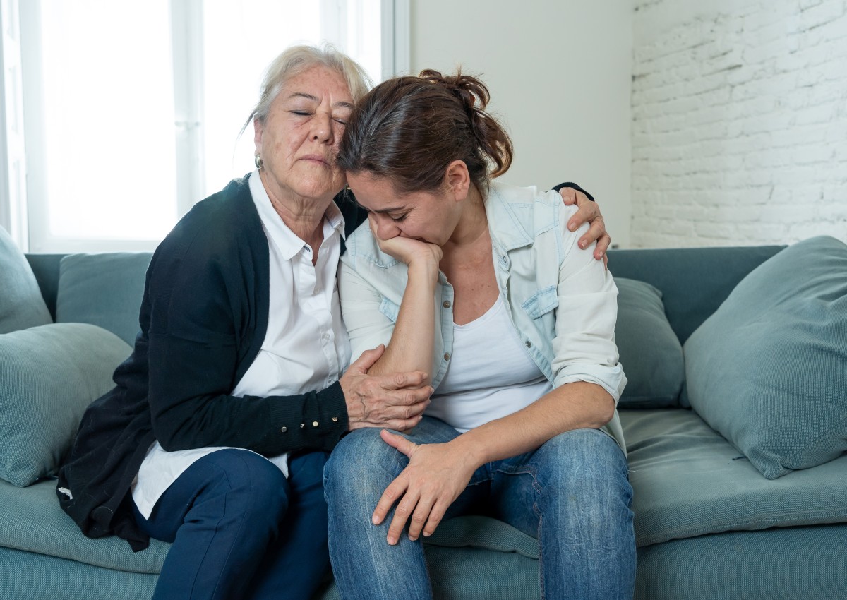older and younger woman seated on couch and grieve loss 366562794